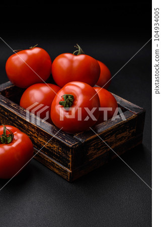 Delicious fresh juicy tomatoes on a dark concrete background Delicious fresh juicy tomatoes on a dark concrete background 104934005