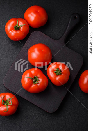 Delicious fresh juicy tomatoes on a dark concrete background 104934020