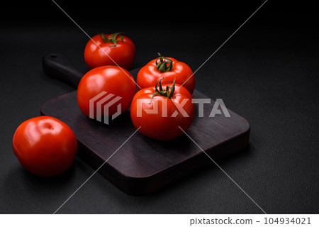 Delicious fresh juicy tomatoes on a dark concrete background 104934021