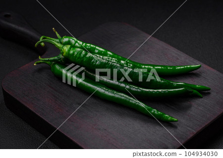 Fresh hot green chili peppers on a dark concrete background Fresh hot green chili peppers on a dark concrete background 104934030