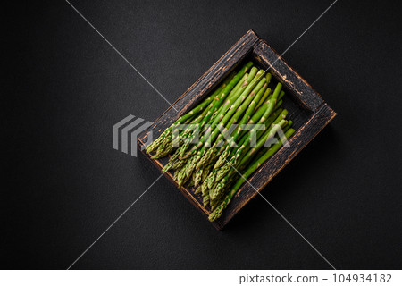 Delicious fresh sprigs of asparagus on a dark textured background 104934182