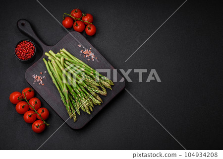 Delicious fresh sprigs of asparagus on a dark textured background 104934208
