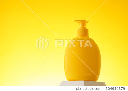 Cosmetic bottle with sunscreen lotion on yellow background Cosmetic bottle with sunscreen lotion on yellow background 104934879