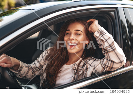 Young smiling woman driving a car in the city Young smiling woman driving a car in the city 104934935