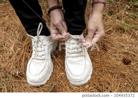 Women's legs tie her shoelace while trekking in the forest 104935372