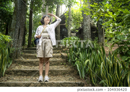 Asian woman looking around in the forest Asian woman looking around in the forest 104936420