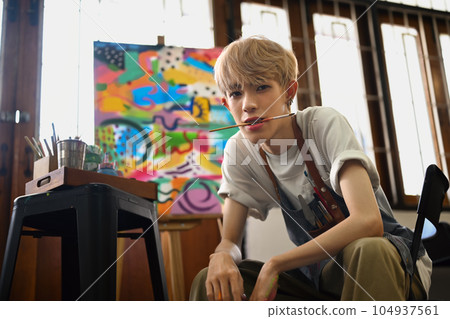 Art, education, creativity and people concept. Asian student man painting on canvas with watercolors at art class 104937561