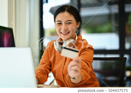 Cheerful young woman holding credit card laptop. E-commerce, banking service and shopping online 104937575