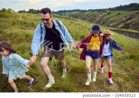 Loving, caring family, man and woman going hiking with their children. Walking on trails, hills, fields Beautiful summer nature landscape Loving, caring family, man and woman going hiking with their children. Walking on trails, hills, fields Beautiful summer nature landscape 104938523