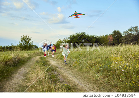 Happy little girl, child running with kite on trail in field. Spending time with parents and sister outdoors on warm summer day 104938594