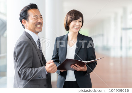 Middle-aged businessmen and women having a meeting in the office Middle-aged businessmen and women having a meeting in the office 104939016