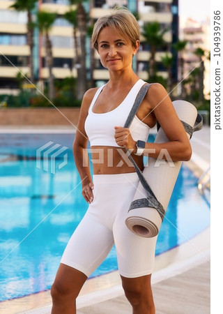 Portrait of young slim and healthy caucasian girl doing workout in park, standing with water bottle 104939786