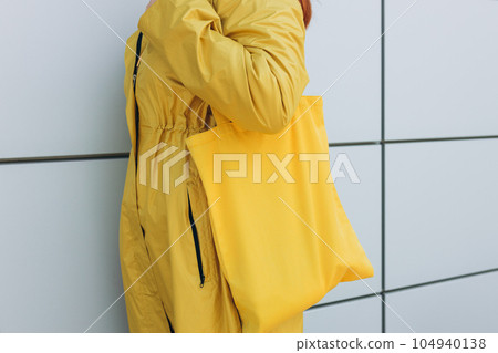 Model hold blank yellow fabric eco bag for save environment on street fashion. Urban mockup of tote bag. Eco Nature Friendly Style. 104940138