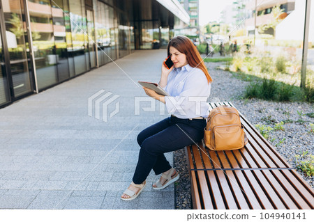 Upset young woman talking over phone disappointed hear bad news, sad pensive girl speaking having unpleasant smartphone conversation and siting on the bench at city street. Negative emotions Upset young woman talking over phone disappointed hear bad news, sad pensive girl speaking having unpleasant smartphone conversation and siting on the bench at city street. Negative emotions 104940141