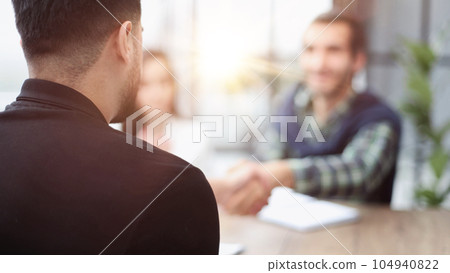 Sits by the table with laptops. Young business people in formal clothes working in the office Sits by the table with laptops. Young business people in formal clothes working in the office 104940822
