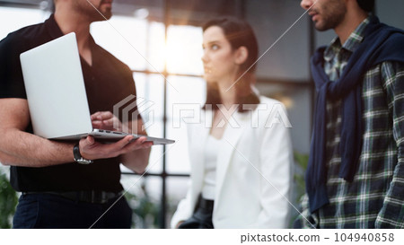 young businessman presenting his business plan on laptop to colleagues 104940858