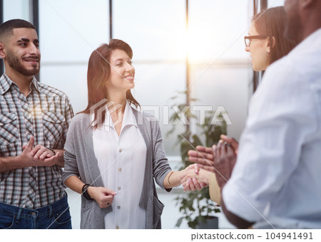 Business people standing and shaking hands in an office building 104941491