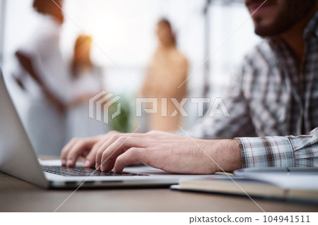 Side view shot of businessman working by using a laptop computer on table. Side view shot of businessman working by using a laptop computer on table. 104941511