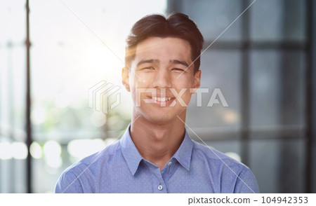 Well dressed young Asian businessman smiling confidently while standing alone in a bright modern office 104942353