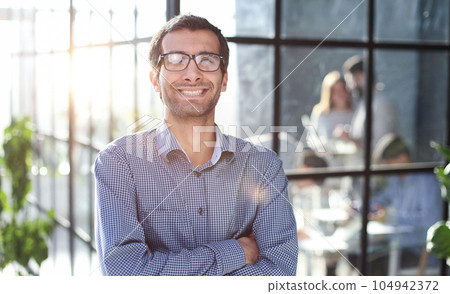 Young businessman in casual clothes stands with his hands on his waist Young businessman in casual clothes stands with his hands on his waist 104942372