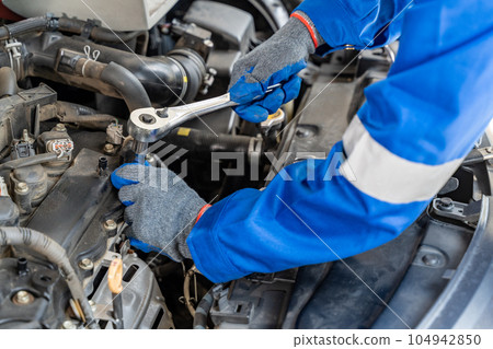 Close up hands of a male car mechanic using retchet wrench working on the car's engine 104942850