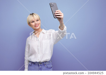 portrait of a young blond business woman with a short haircut in a white shirt taking a selfie on portrait of a young blond business woman with a short haircut in a white shirt taking a selfie on 104944525