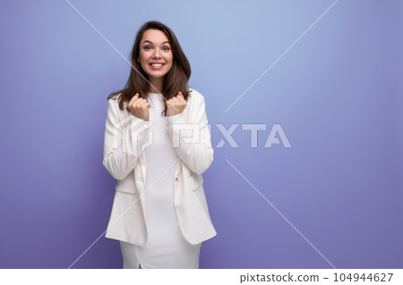 energetic young woman with dark hair below the shoulders of a model appearance dances on a studio 104944627