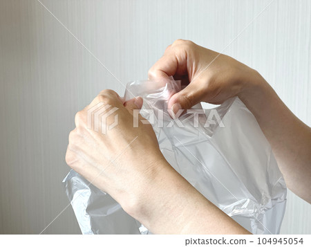 Hand trying to open a plastic bag Hand trying to open a plastic bag 104945054