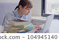 Business woman working on a computer while looking at materials 104945140