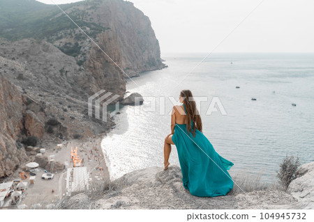 Woman sea trevel green dress. Side view a happy woman with long hair in a long mint dress posing on a beach with calm sea bokeh lights on sunny day. Girl on the nature on blue sky background. 104945732
