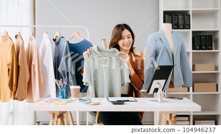 Fashion blogger concept, Young Asian women selling clothes on video streaming.Startup small business SME, using smartphone or tablet taking receive and checking. 104946237