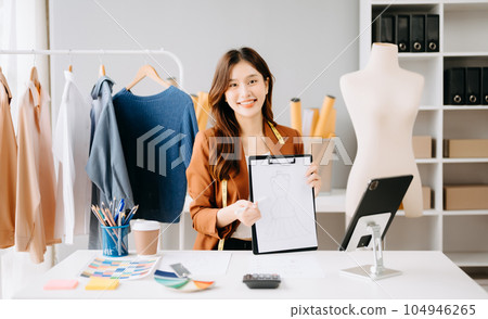 Asian tailor woman working on clothes in tailoring atelier. beautiful young female fashion designer smile and after success in studio.. Asian tailor woman working on clothes in tailoring atelier. beautiful young female fashion designer smile and after success in studio.. 104946265