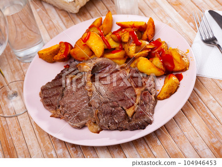 Tasty beef steak with baked potatoes and ketchup 104946453