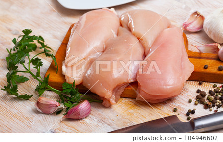 Raw uncooked chicken breast fillet with garlic and greens Raw uncooked chicken breast fillet with garlic and greens 104946602