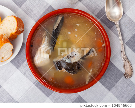 Salmon head soup with potatoes and carrots in clay bowl 104946603