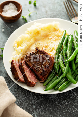 Traditional dinner meal with a bacon wrapped steak and potatoes 104946684
