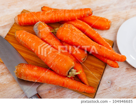 Bunch of fresh carrots on wooden cutting board 104946685