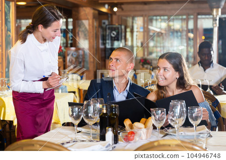Woman waiter is taking order from clients in restaurante 104946748
