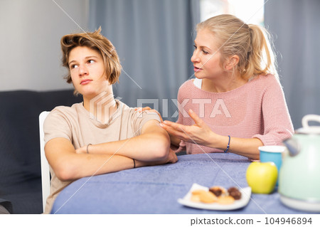 Offended teenager is soothed by caring mom at table at home 104946894