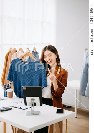 Fashion blogger concept, Young Asian women selling clothes on video streaming.Startup small business SME, using smartphone or tablet taking receive and checking. 104946963