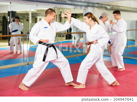 Young woman in kimono sparring with male partner during martial arts training 104947041