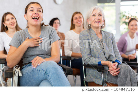 small group of women are sitting in audience, listening to lecture and laugh at amusing case 104947110