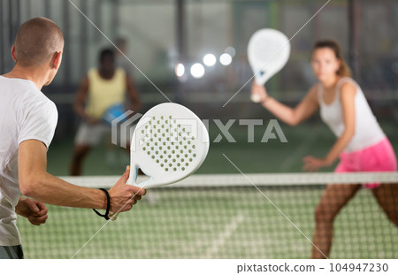 Rear view of man with white racket playing padel 104947230