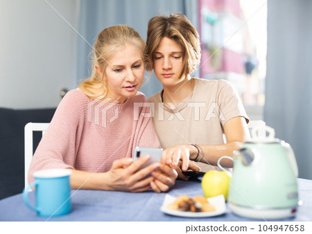 Mother and son using phones during breakfast 104947658