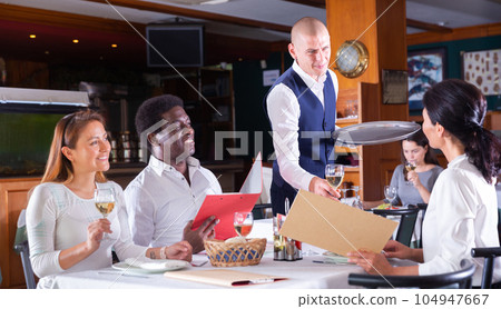 male waiter serving order to friends in restaurante male waiter serving order to friends in restaurante 104947667
