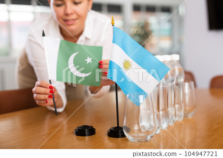 Little flag of Argentina on table and flag of Pakistan put next to it by young woman Little flag of Argentina on table and flag of Pakistan put next to it by young woman 104947721