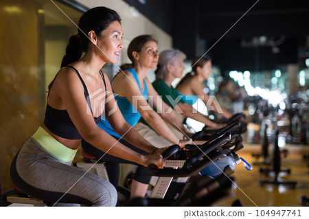 Woman on stationary bike workout in gym 104947741