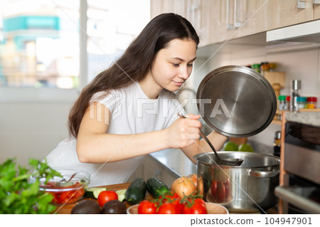 Portrait of young woman cooking at home 104947901