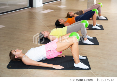 Aerobics pilates women with toning balls in row on fitness class 104947948