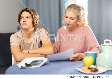Frustrated teenage boy with worried mother reading paper letter 104947955
